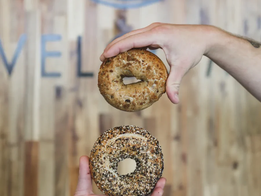 hands holding two bagels in front of K Brew logo